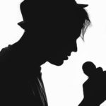 The silhouette of a man holding a microphone