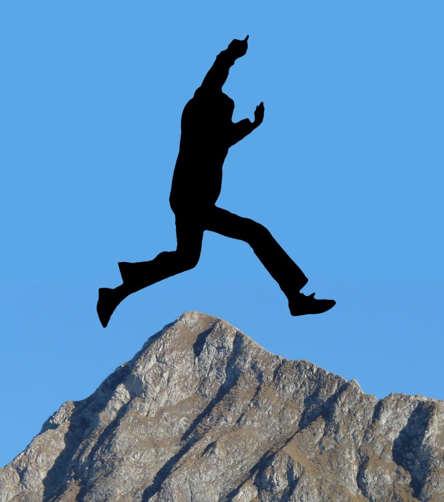The silhouette of a man leaping over a mountain top